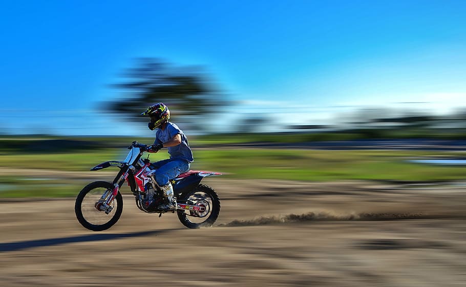 panning photography of man riding motocross dirt bike, speed