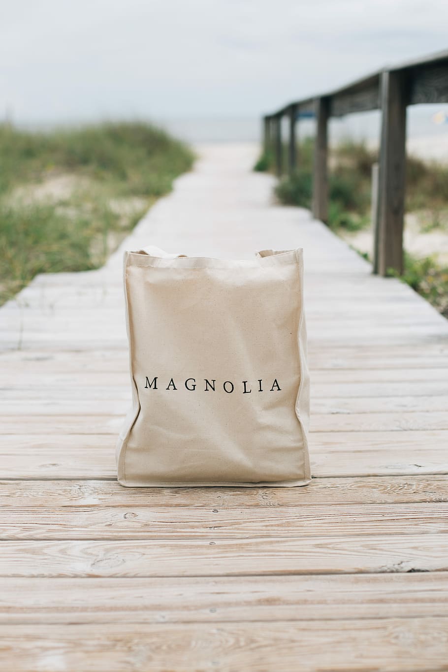 bag sitting on a dock, shallow focus photography of Magnolia bag on wooden dock
