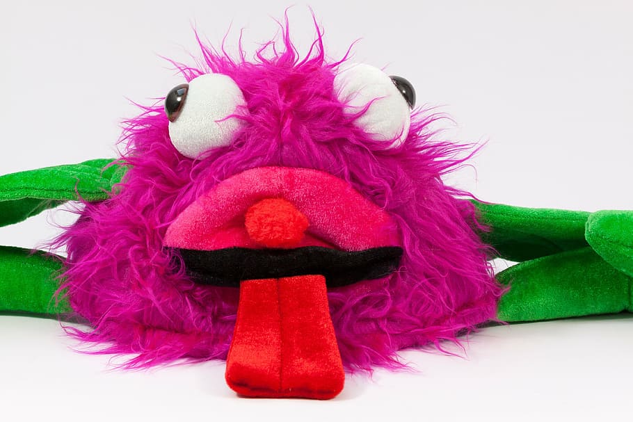 purple monster sticking tongue out toy on white surface, carnival