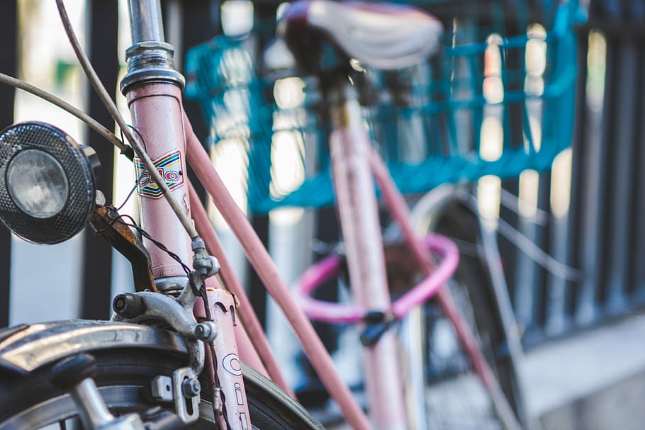 brown bike beside black fence, pink city bike parked on gray metal fence HD wallpaper