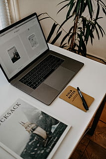 MacBook Pro on white table, black pen near black and grey laptop on white desk HD wallpaper