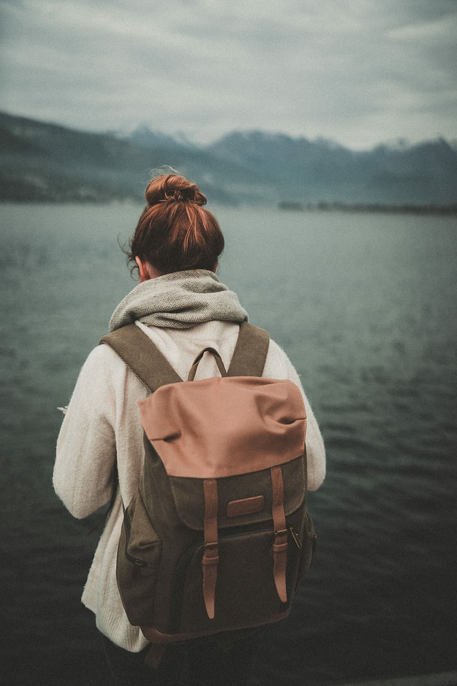 woman standing nearby calm body of water ], woman in white jacket with brown backpack standing over body of water, HD wallpaper