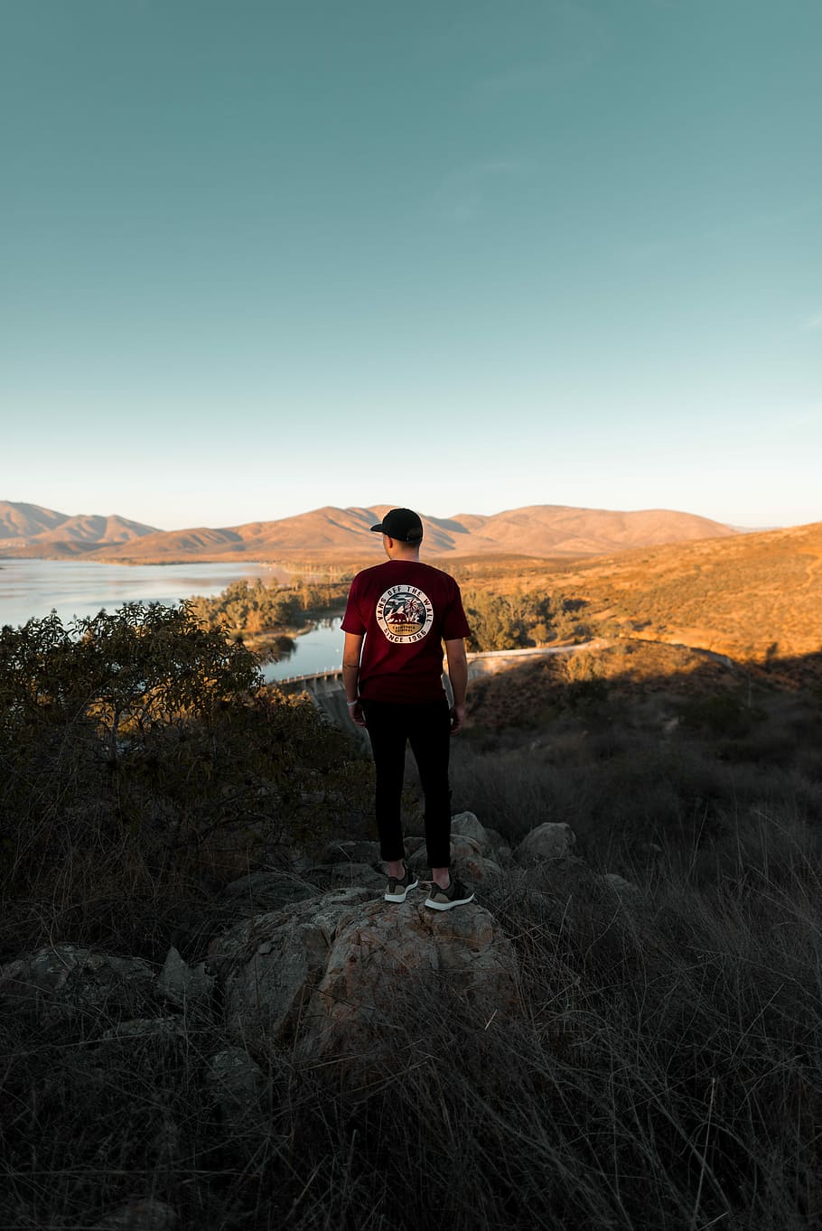 man standing on rock while watching landscapes, man standing on brown stone HD wallpaper