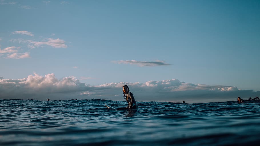 person sitting on surfboard surrounded by blue ocean during daytime, person on body of water HD wallpaper