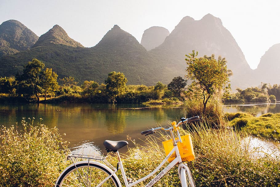 bike in front of trees with lake, cruiser bicycle near body of water overlooking mountain range HD wallpaper