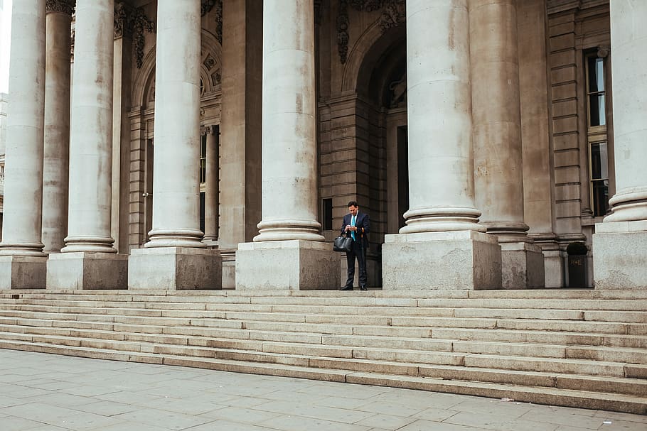 man standing in the middle of pillar building, man standing at front of doorway HD wallpaper