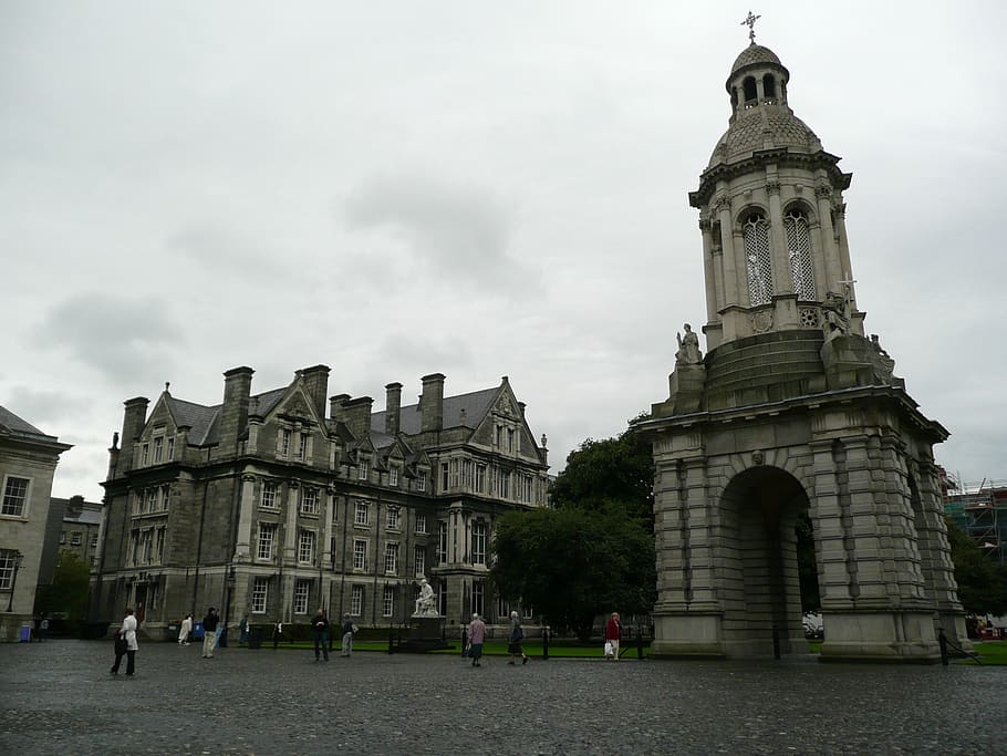gray tower beside buildings under cloudy day sky, trinity college