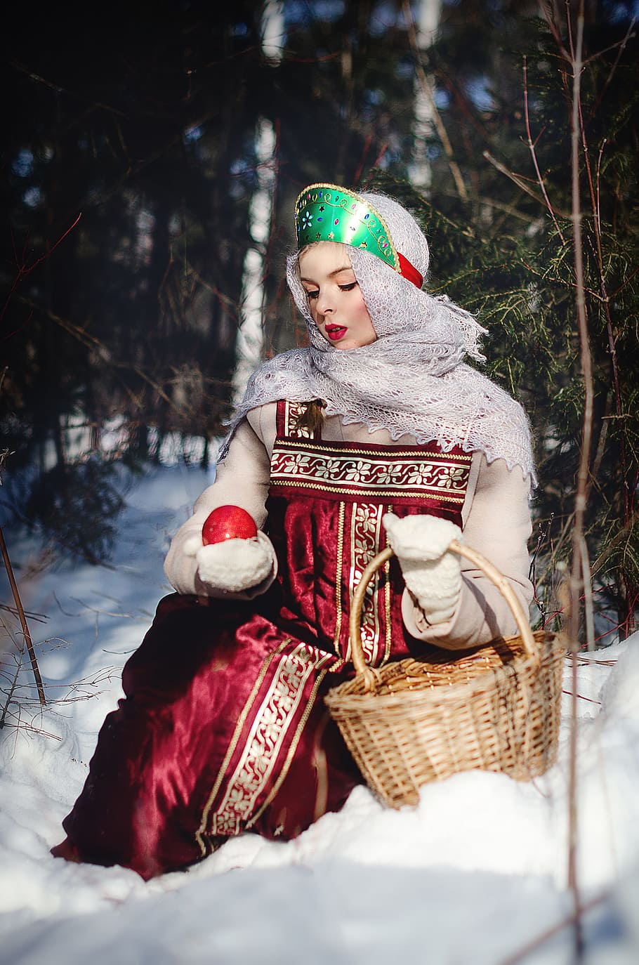 woman sitting on snow holding red apple, winter, christmas, coldly