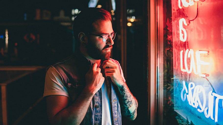 man holding his denim vest looking at widnow, man standing near neon light signage on wall inside room, HD wallpaper