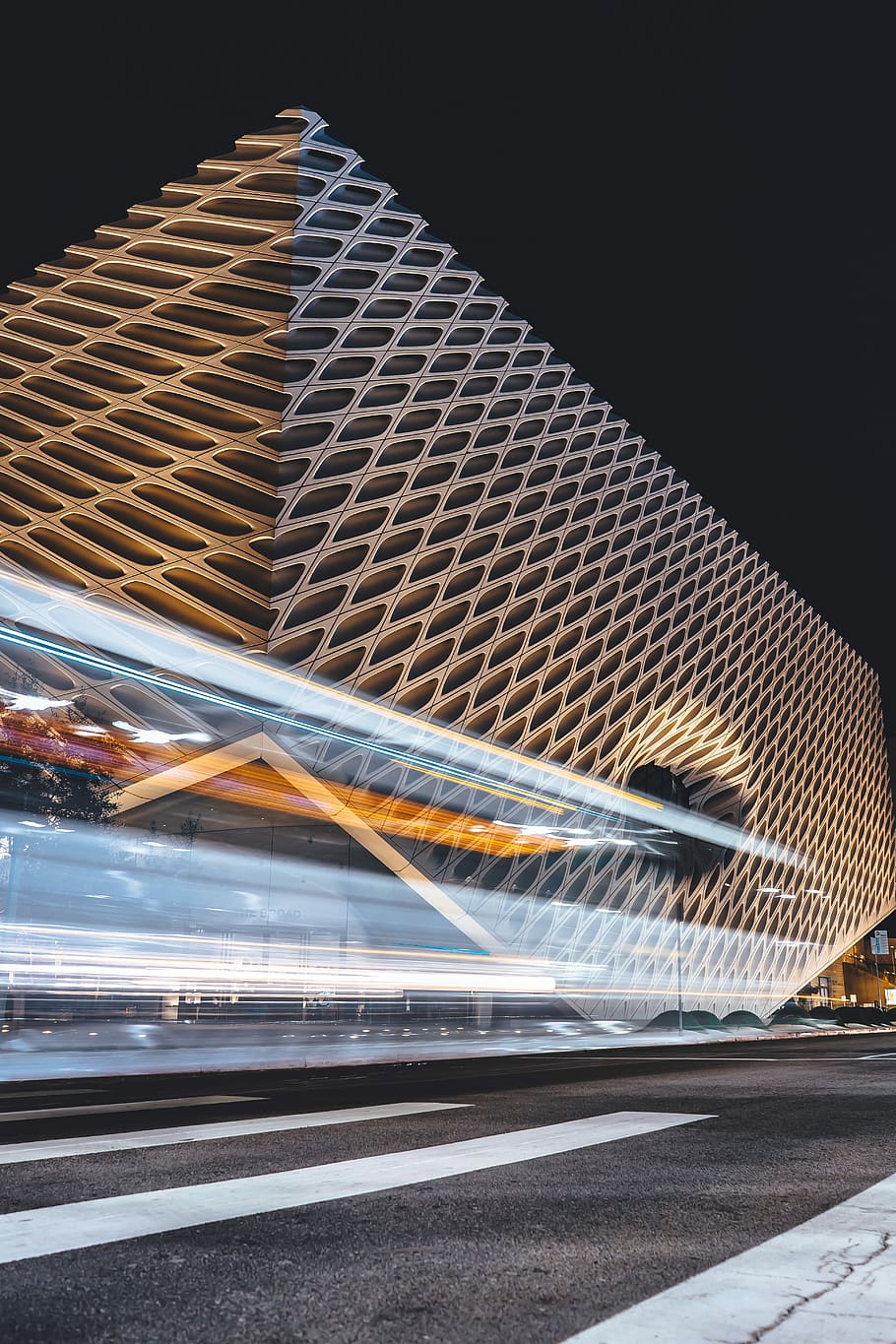 white and grey pedestrian lane paint front of glass building at night, time lapse photo of building under dark sky HD wallpaper