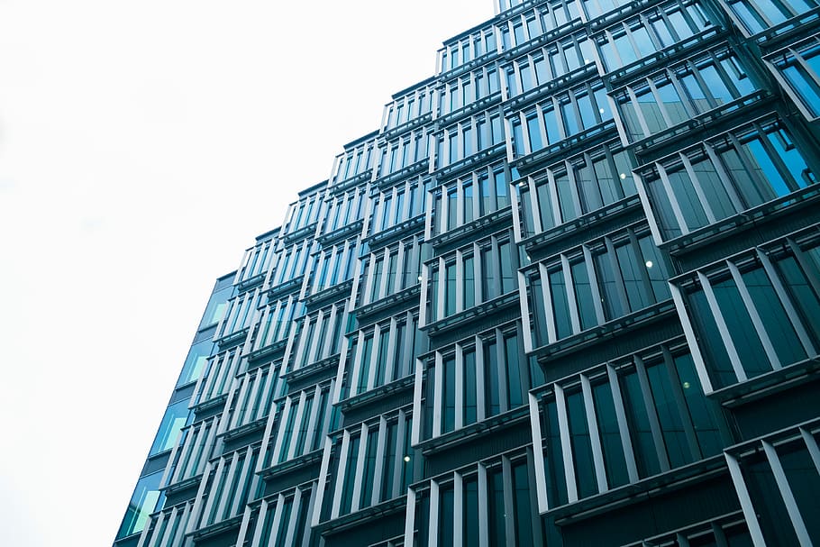 low angle photography of curtain wall building at daytime, gray concrete high-rise building under white sky HD wallpaper