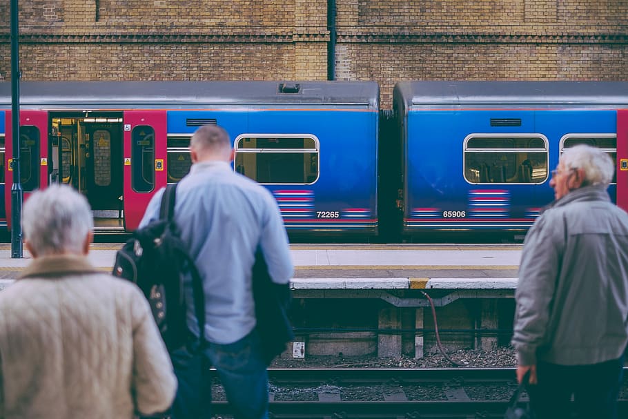 person in gray dress shirt standing in front of train rail, three persons standing beside train HD wallpaper