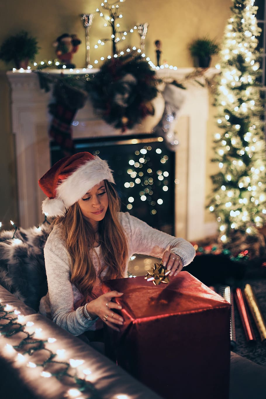 woman putting ribbon in red gift box near lighted Christmas tree inside room, women's gray long-sleeved shirt HD wallpaper