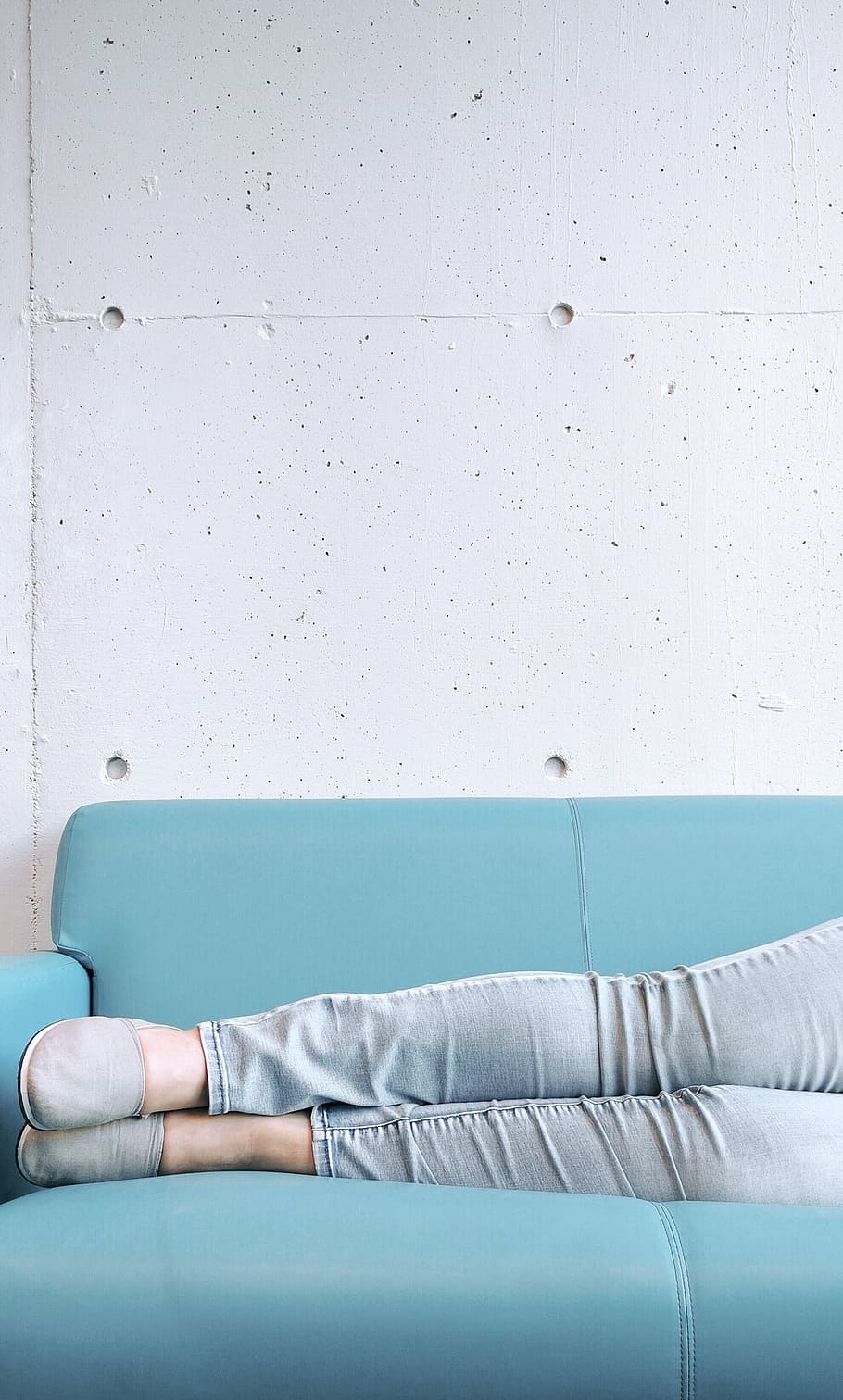 person wearing gray skinny jeans and slip on shoes on a sky-blue couch HD wallpaper