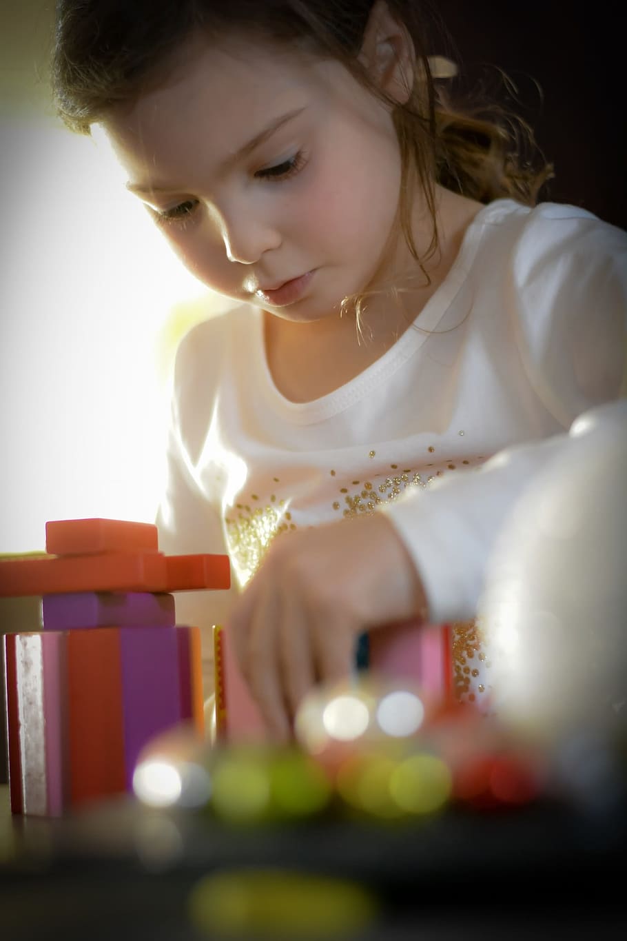 girl in white long-sleeved shirt playing toy, concentration, games