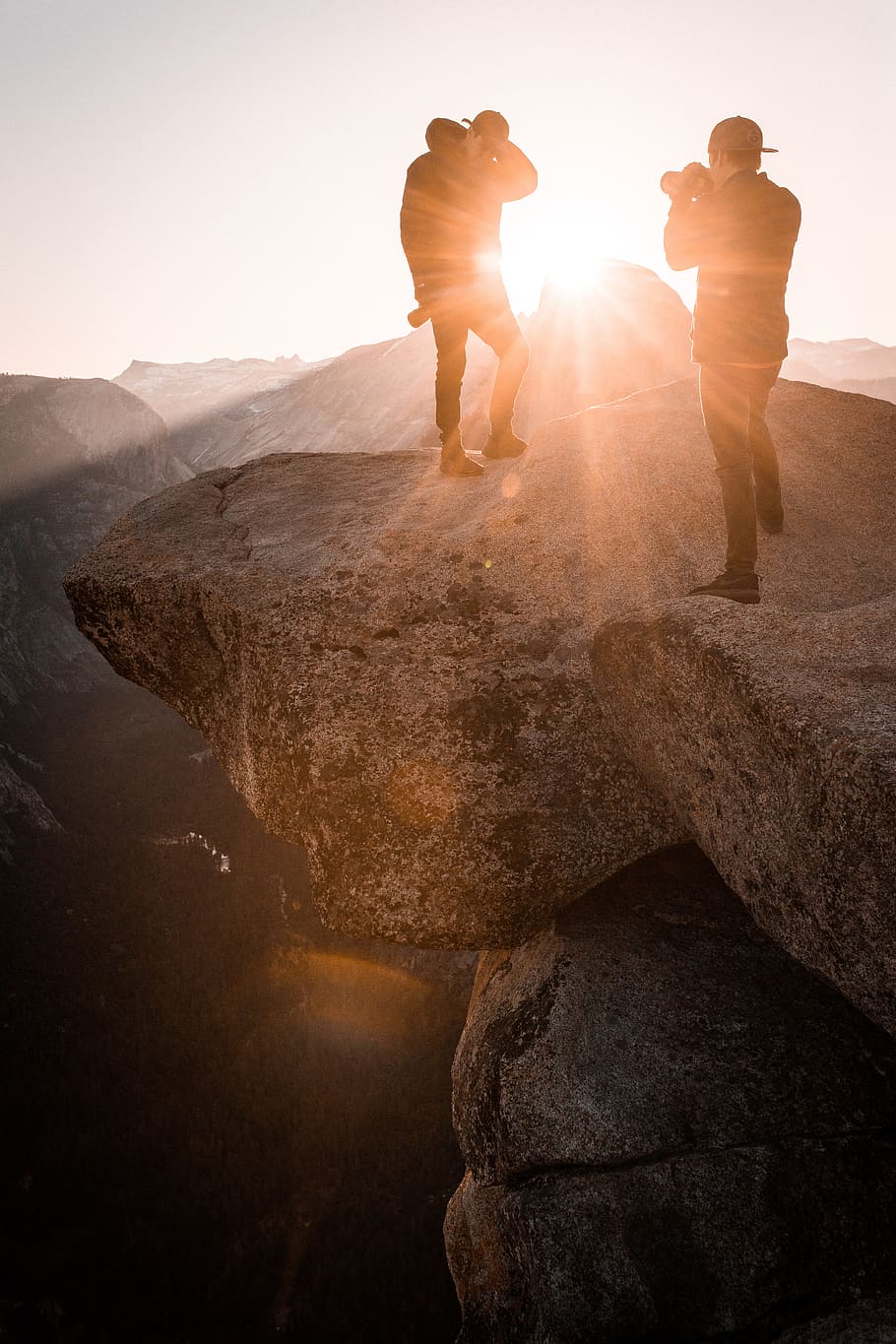 two man on top or rocky mountain, two men standing on boulder taking photo HD wallpaper