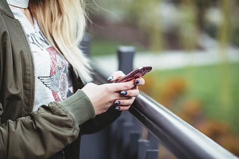 woman holding red phone, woman wearing green full-zip jacket using red smartphone HD wallpaper
