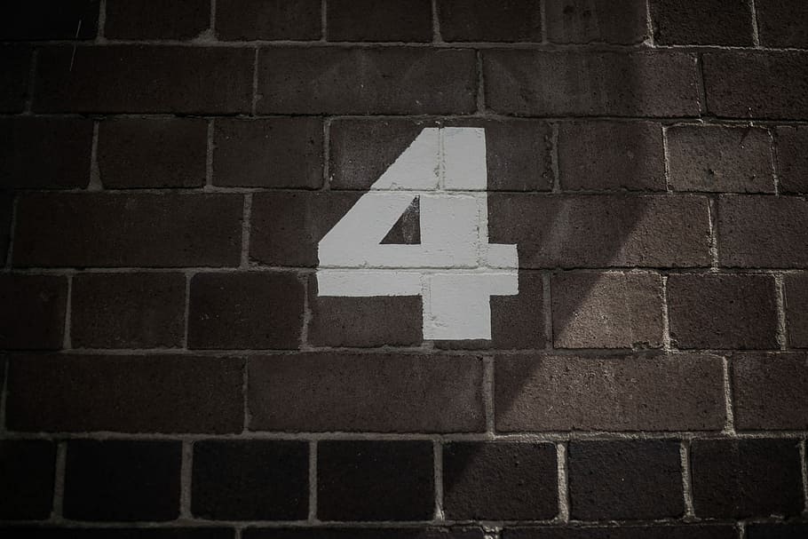 number 4 painting on wall, white 4 print on brown brick wall
