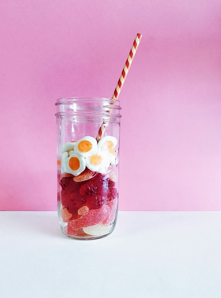 clear glass bottles with jelly beans and straw, egg and pink candies in mason jar with straw