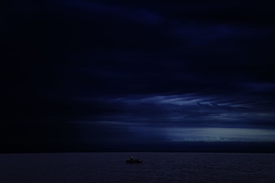 sailing boat on calm body of ocean during dark sky, boat travelling during nighttime