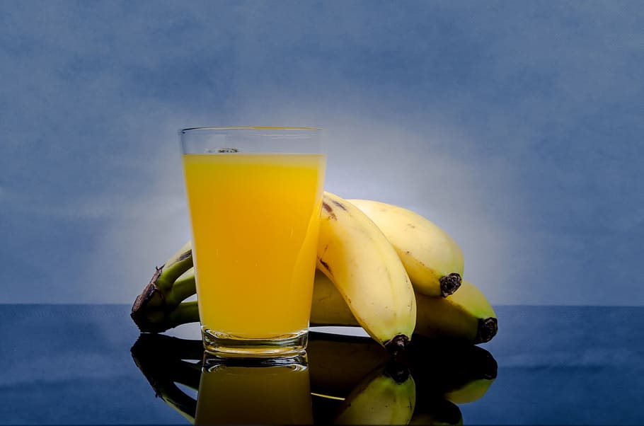 yellow Banana fruit and drinking glass with yellow liquid, juice