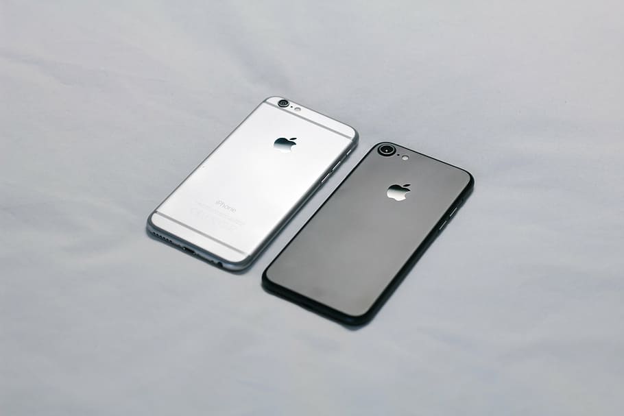 black iPhone 7 and space gray iPhone 6 on grey textile, photo