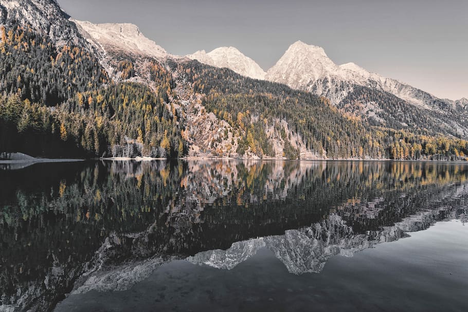 lake in shallow focus photography, green and white mountains with trees near body of water HD wallpaper