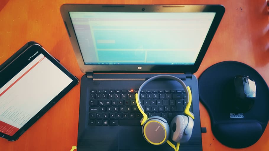 black laptop computer, wireless mouse, tablet computer, and yellow headphones on top of brown wooden furniture HD wallpaper