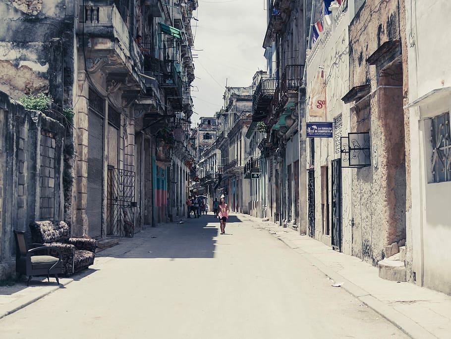 person walking towards between white and black concrete building at daytime, person in pink top surrounded of houses HD wallpaper