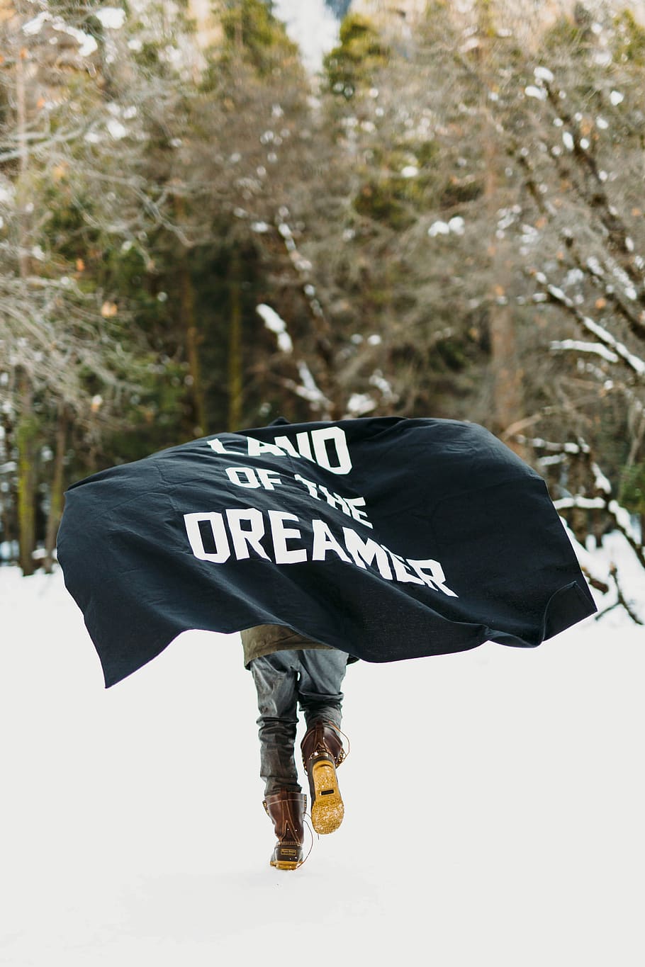 person running on snow with black textile, person carrying Land of the Dreamer-printed banner on snowfield HD wallpaper