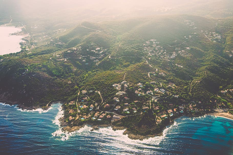 bird's eye view photo of green mountain peak near body of water, aerial photo of town near sea HD wallpaper