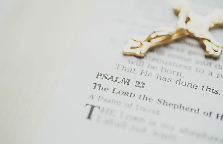 gold-colored crucifix, gold-colored cross pendant on bible showing Psalm 23