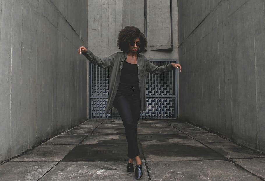 women's standing in middle of alley, woman wearing gray jacket standing between buildings HD wallpaper