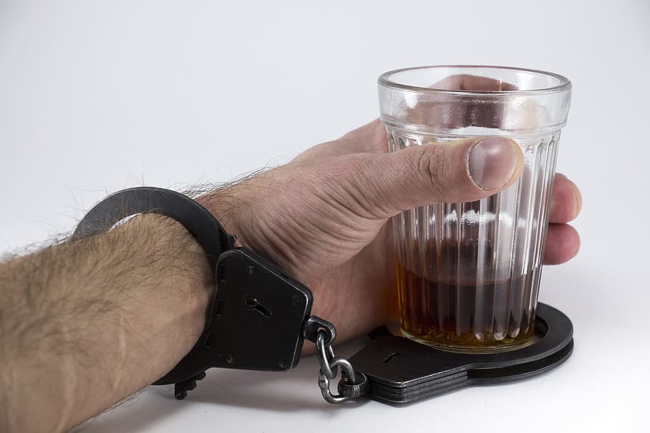 person wearing black handcuff and holding clear glass cup, Alcohol