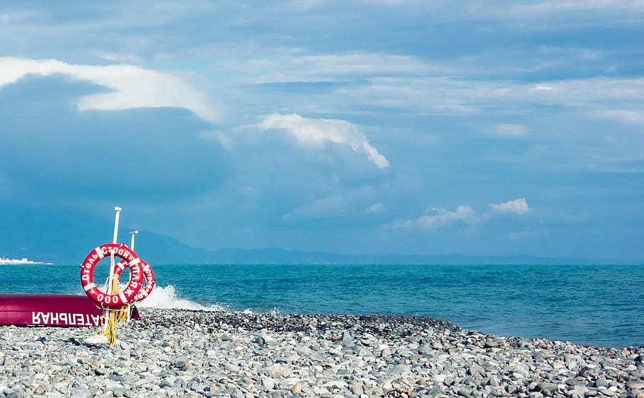 Red and White Ring Signage on Gravel Near Body of Water Under Blue and White Sky HD wallpaper