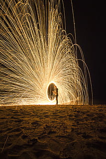 person holding fireworks on beach during nighttime, lights HD wallpaper