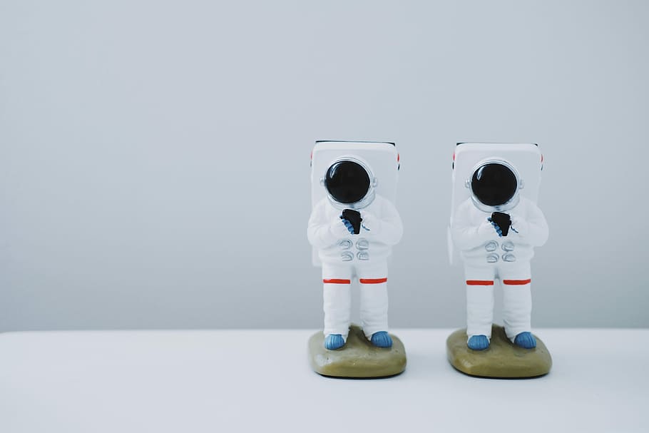 two spacesuit figurines on white surface, two astronaut figurines HD wallpaper