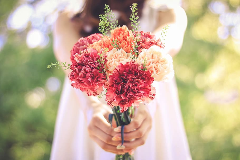 selective focus photography of woman holding bouquet of flowers HD wallpaper