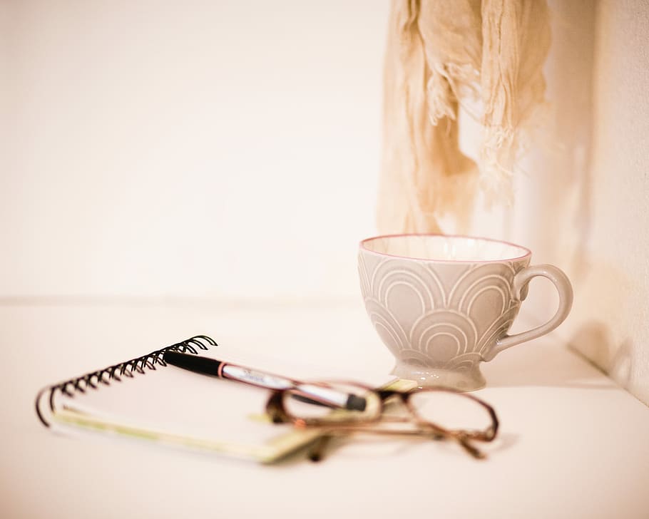 brown framed eyeglasses beside gray cup, gray tea cup near black eyeglasses and pen on notebook HD wallpaper