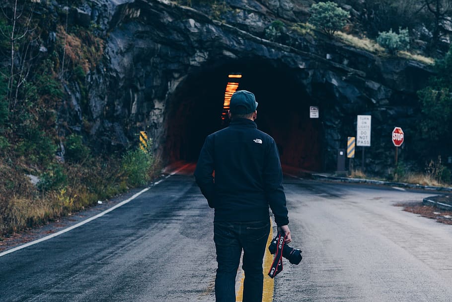 man holding DSLR camera near tunnel road, black, jacket, going, HD wallpaper