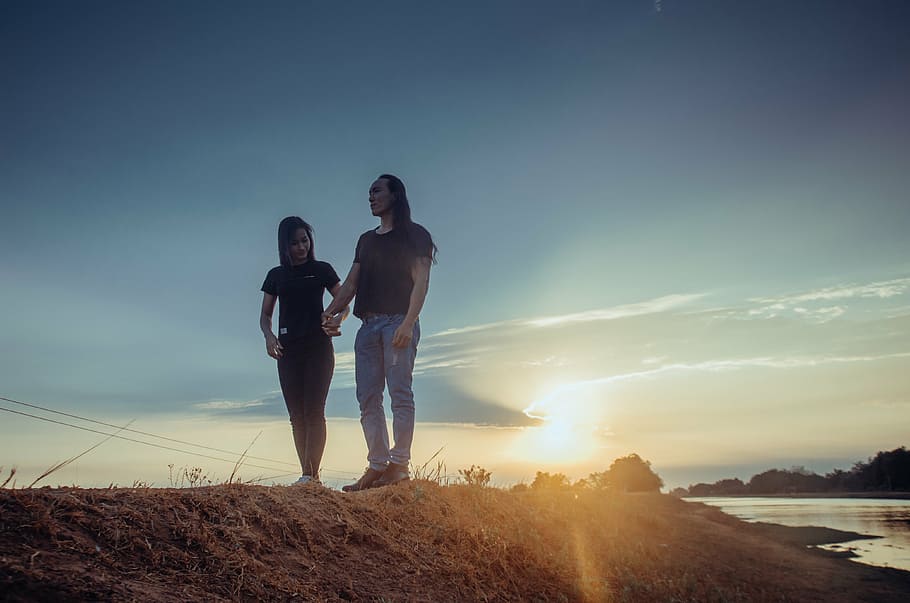 two women on top of hill near body of water at golden hour HD wallpaper