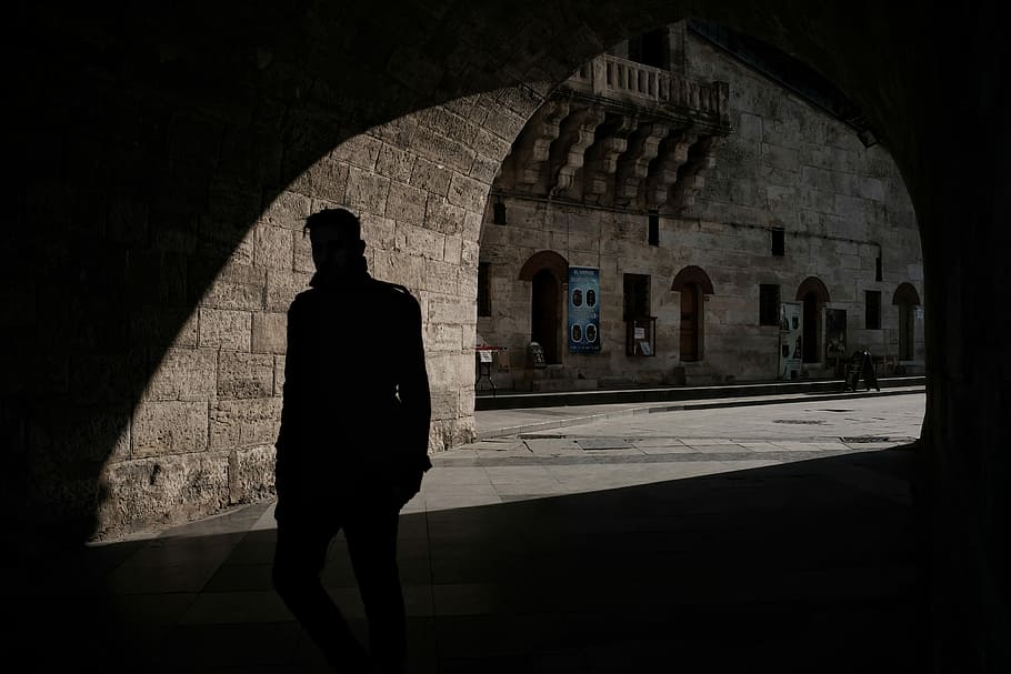 silhouette of man inside of tunnel during daytime, silhouette photo of man standing on tunnel HD wallpaper