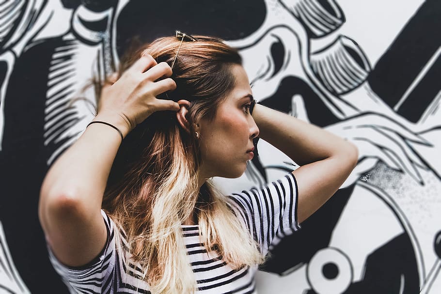 woman in black and white striped top standing near wall with graffiti, woman touching her hair HD wallpaper