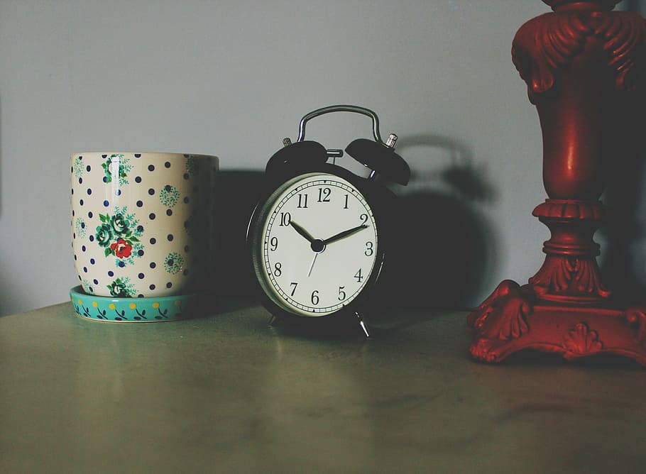 twin bell alarm clock displaying 10:11, black, white, vase, brown