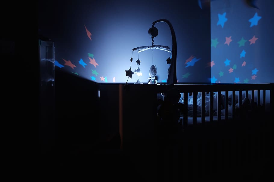 baby's black wooden crib with LED crib mobile, lighted crib mobile in dark room HD wallpaper