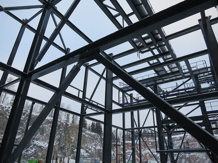 metal building frame beside snow covered hills, construction