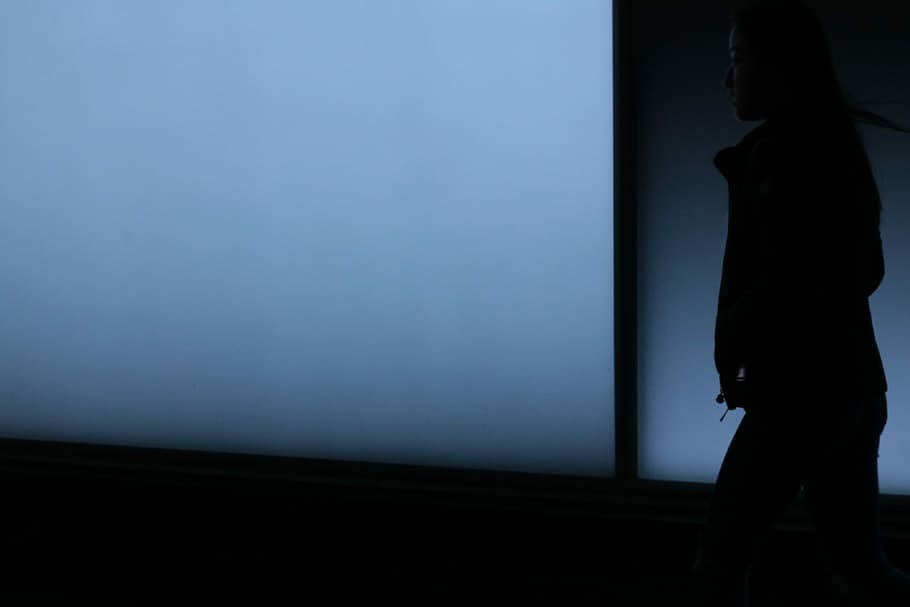 silhouette photo of woman looking at white surface, woman walking on dark area with hands in jacket HD wallpaper