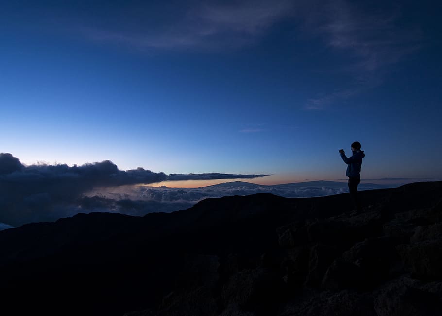 silhouette of man taking photo on rock cliff, silhouette of person standing on top of mountain HD wallpaper