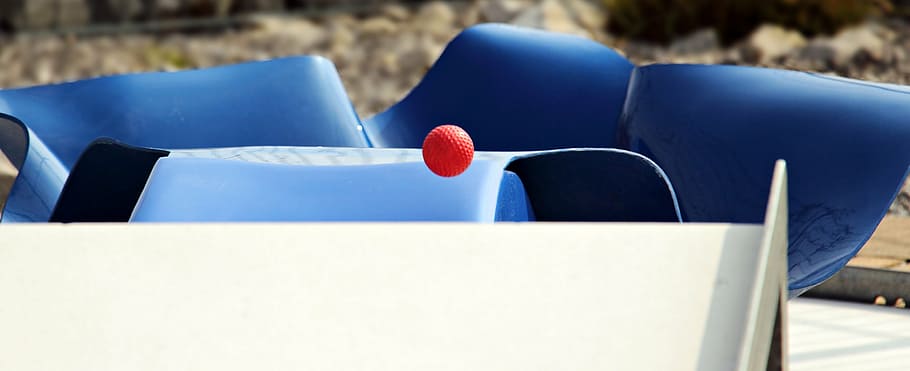red ball over white panel near gray rail during daytime, miniature golf