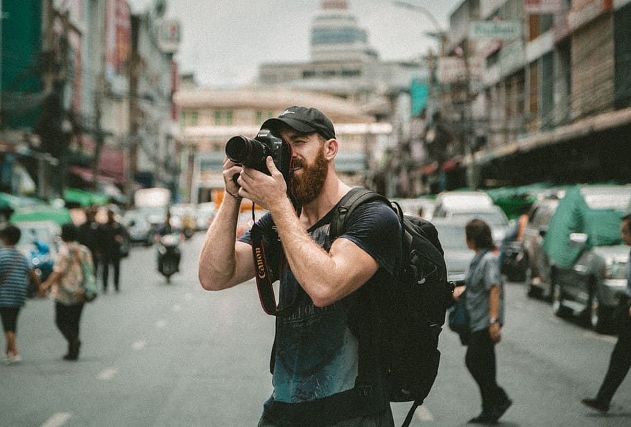 shallow focus photography of man using a DSLR camera, selective focus photo of man wearing black t-shirt about to take picture